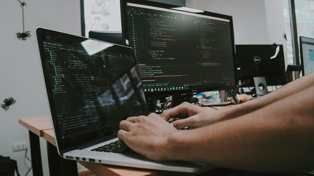 programmer writing code on laptop